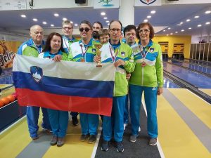 Udeleženci EP v steznem kegljanju stojijo na kegljišču s slovensko zastavo in pokalom